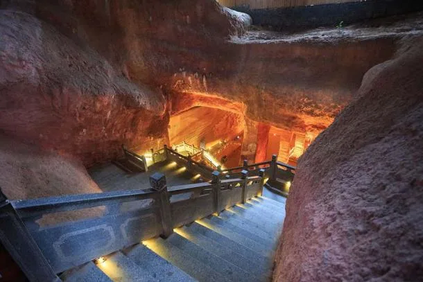 Interior iluminado das cavernas de Longyou na China, com paredes esculpidas manualmente e detalhes geométricos misteriosos.